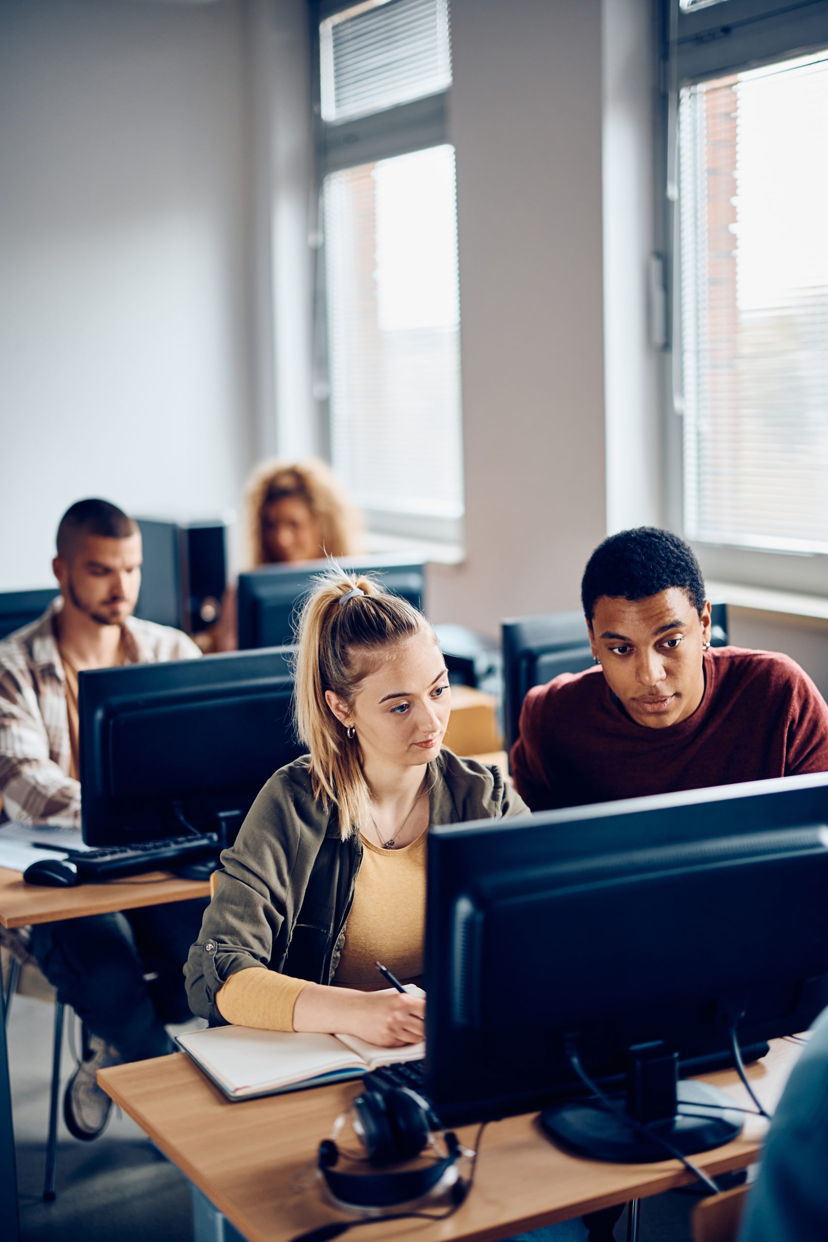 Young students sitting at a computer, looking at the screen