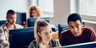 Young students sitting at a computer, looking at the screen